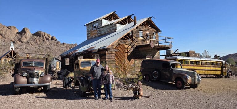 Two people at a Nevada ghost town near Las Vegas, with vintage cars, old school bus, ideal for sightseeing and ATV tours.