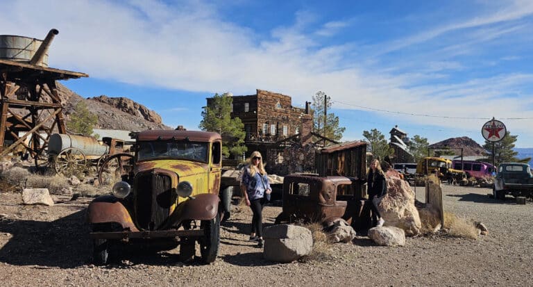 Two women explore vintage cars in a Nevada ghost town near Las Vegas—perfect for sightseeing and off-road ATV adventures.