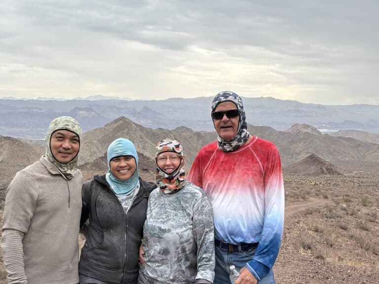 Group in outdoor gear smiling in Nevada desert near Las Vegas, with rocky hills—perfect for ATV tours or Colorado River adventures.