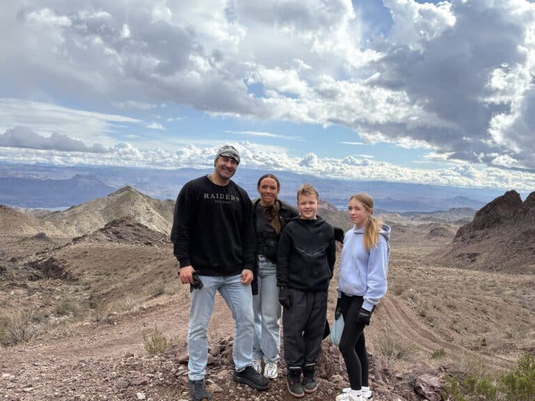 Group in casual outdoor gear stands on rocky Nevada terrain near mountains, ideal for Las Vegas ATV tours and Ghost Town sightseeing.