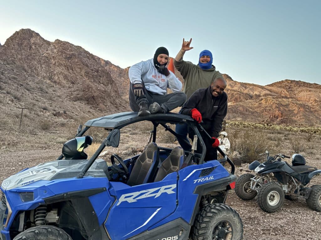 Three people enjoy a RZR off-road ride in Nevada's rocky desert near Las Vegas; ATV tours and Ghost Towns in the backdrop.