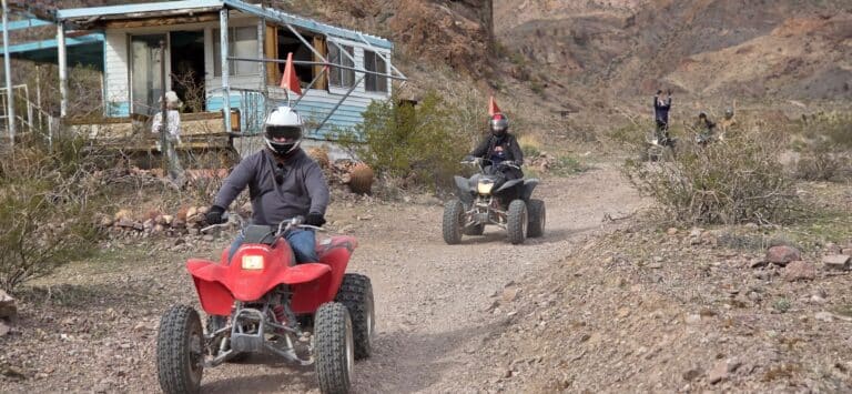 ATV riders explore a rocky Nevada desert trail near an old cabin, with ghost town views and mountains outside Las Vegas.