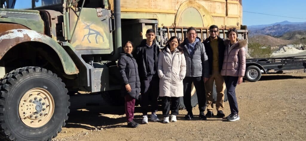 Six people in winter jackets by a green military truck near Nevada mountains, ready for ATV tours outside Las Vegas.