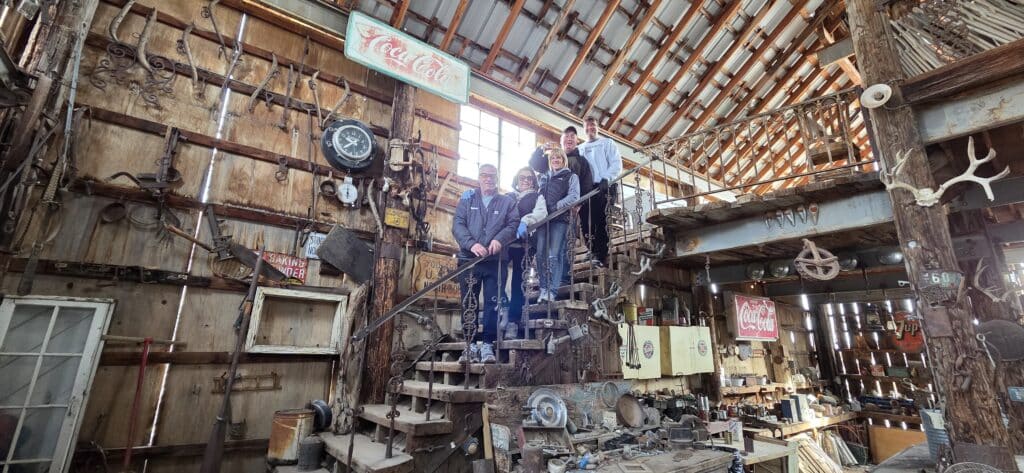 Four people on a rustic staircase in a Nevada ghost town barn packed with antiques, perfect for Las Vegas ATV tours or sightseeing.
