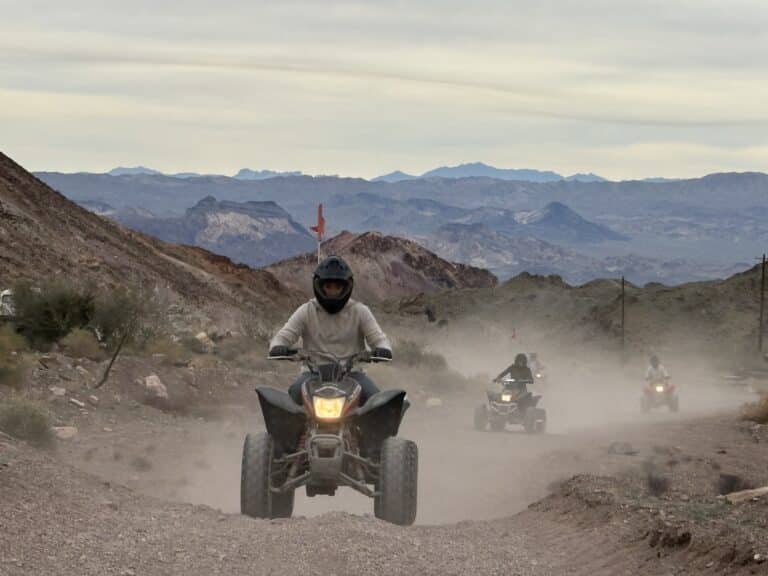 Riders enjoy an ATV tour near Las Vegas, cruising dusty desert trails with views of Nevada hills and distant mountains.