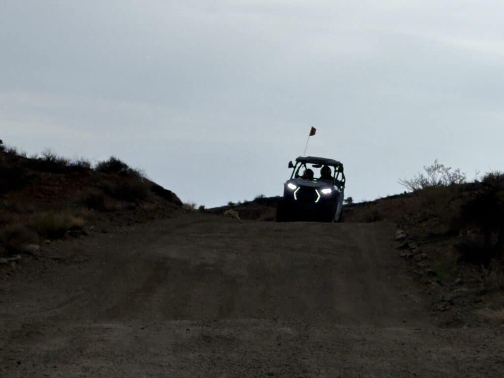 ATV with headlights on rides a Nevada dirt trail near Las Vegas, perfect for RZR off-road tours and Colorado River views.