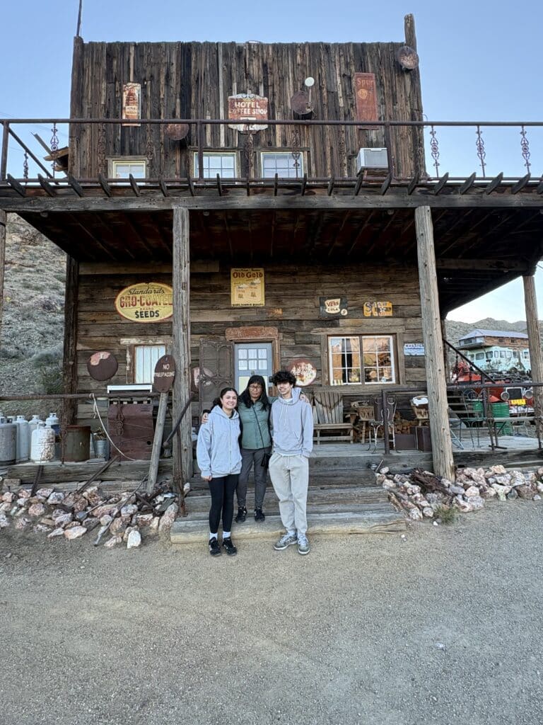 Smiling group in front of rustic Nevada ghost town building with vintage signs—perfect for Las Vegas ATV tours or sightseeing.