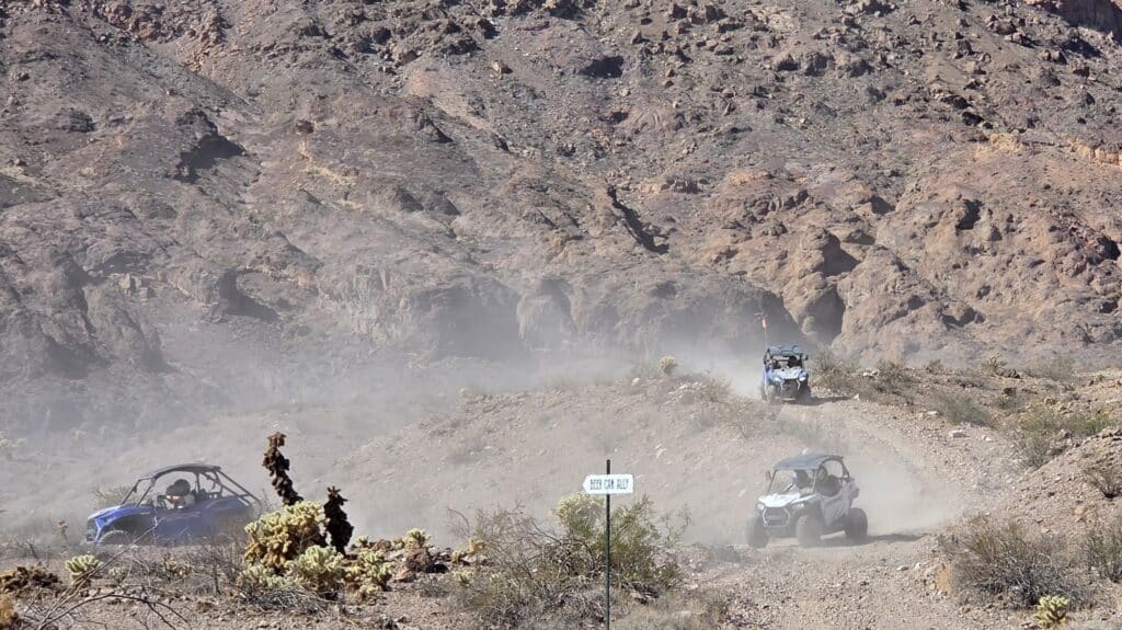 ATV vehicles on a Nevada desert trail near Las Vegas, with Gold Mine ATV Tour sign and rocky Eldorado Canyon hills in view.
