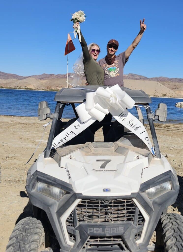 Happy couple in RZR off-road vehicle by Colorado River near Las Vegas, Nevada—ready for ATV adventure tour and sightseeing.