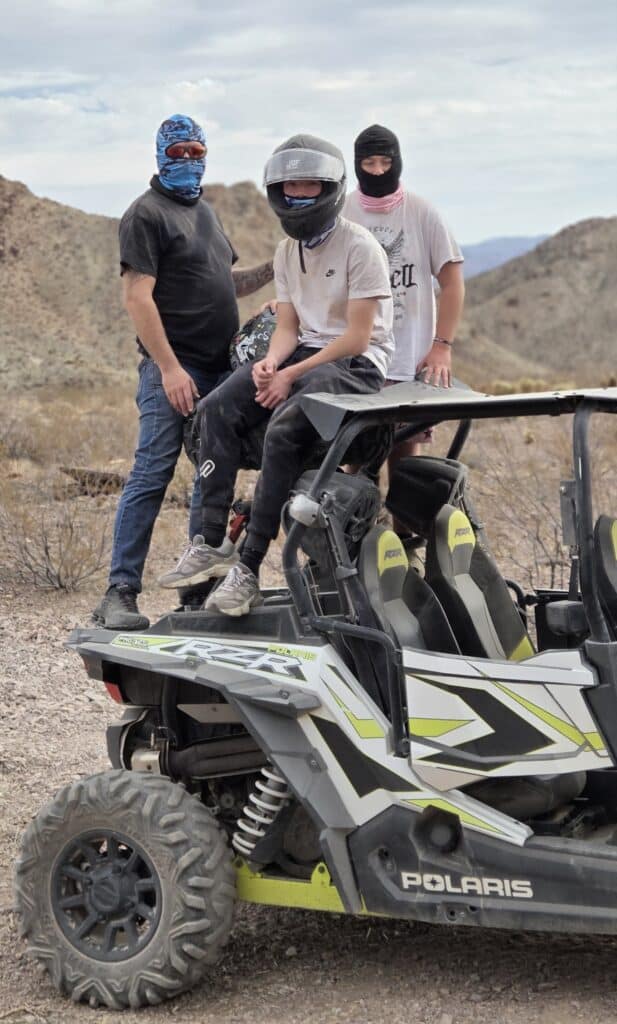 Adventurers in helmets with a Polaris RZR during an ATV tour near Eldorado Canyon, Las Vegas, Nevada desert hills.