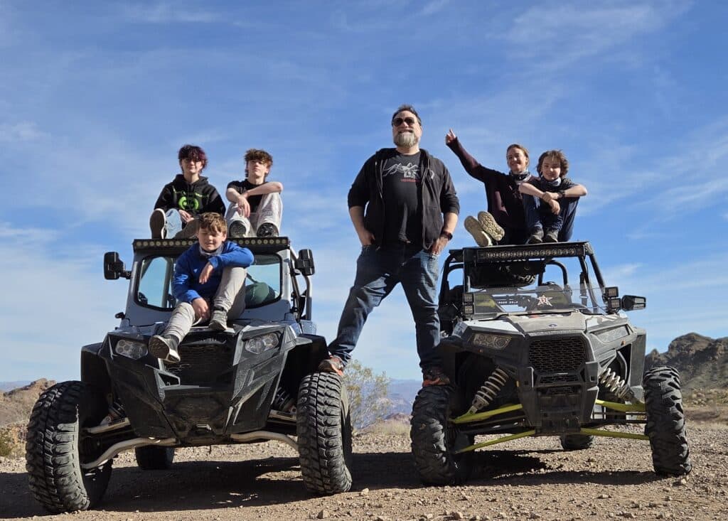 Family enjoys a Las Vegas ATV tour near Nevada mountains, with kids on off-road vehicles under blue skies.