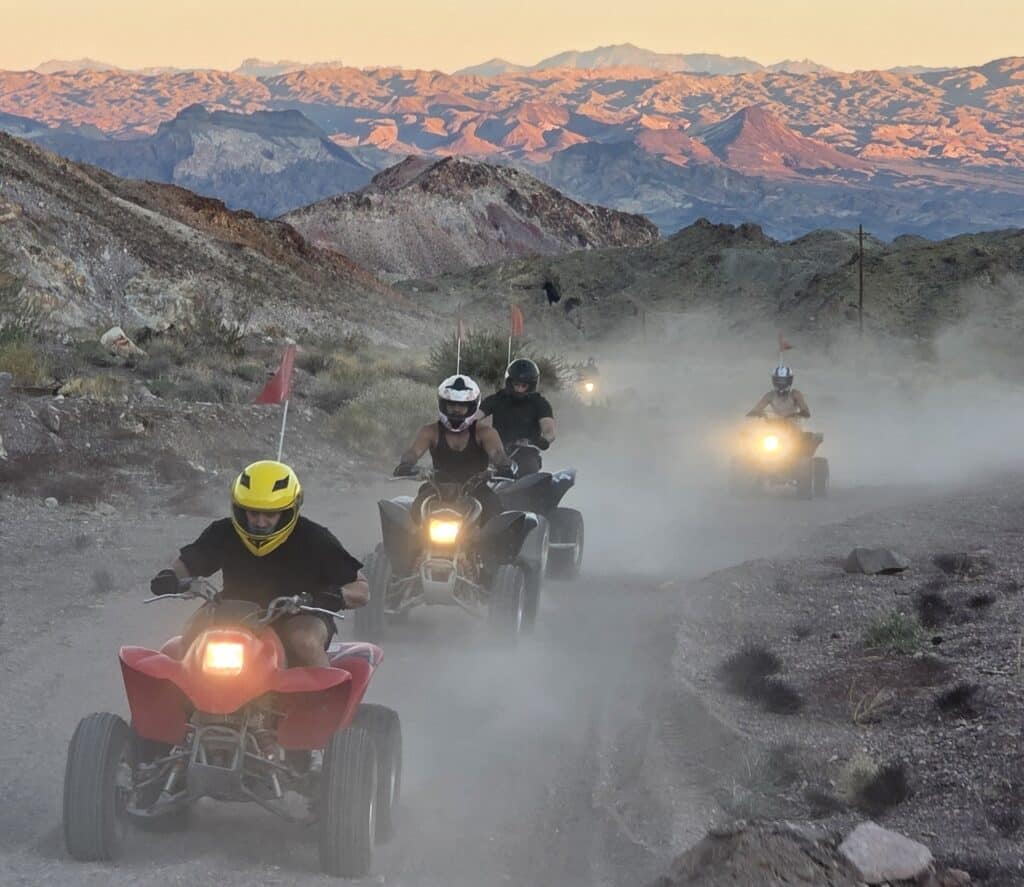 Adventurers enjoy an ATV tour near Las Vegas, riding dusty trails through Eldorado Canyon’s Nevada mountains at sunset.
