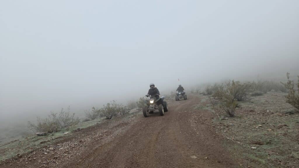 Adventurers ride ATVs on a foggy Nevada trail near Las Vegas, exploring rugged terrain on a thrilling off-road ATV tour.