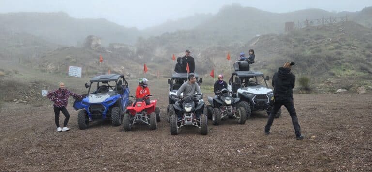 Group enjoying an ATV tour and RZR off-road adventure near the Colorado River, Nevada, with misty mountains in the background.