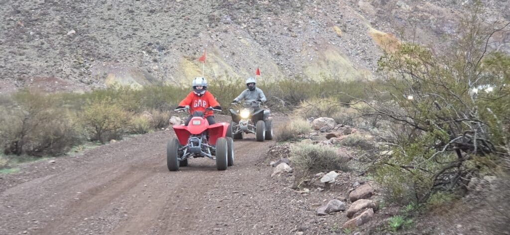Riders on ATVs explore Eldorado Canyon near Las Vegas, Nevada, with red flags flying—ideal for ATV tours by the Colorado River.