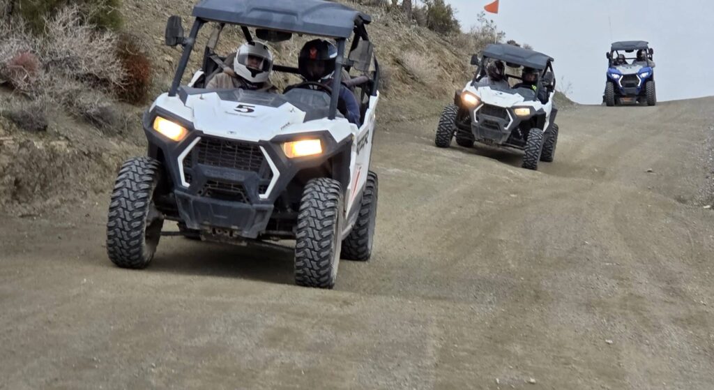 ATVs traverse a dusty Nevada desert trail near Las Vegas on an exciting RZR off-road tour, sparse bushes lining the route.