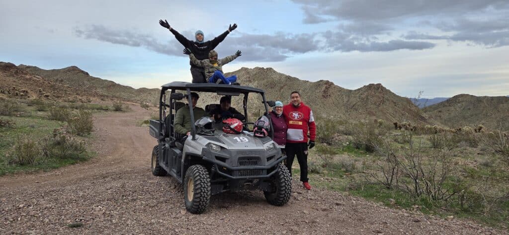 Group enjoys Las Vegas ATV tour on rocky desert trails near Eldorado Canyon, Nevada, with Colorado River views and mountains.