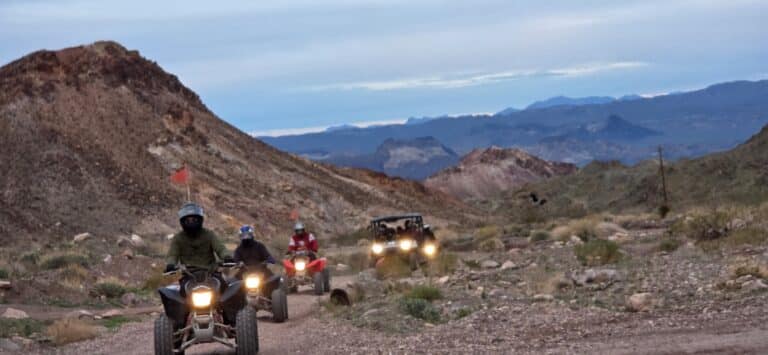Adventurers enjoy ATV tours and RZR rides on a rugged Nevada desert trail near Las Vegas with mountains in the distance.