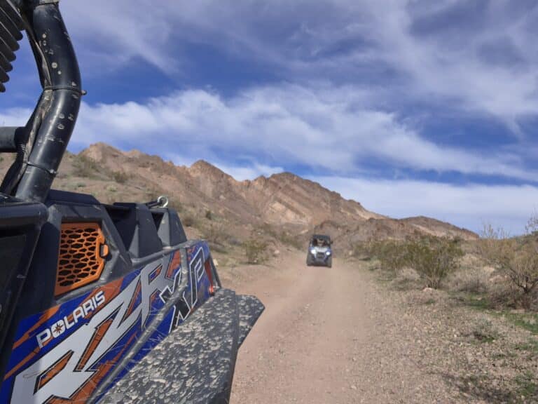 RZR off-road vehicles on a Nevada desert trail near Las Vegas, mountains behind, close-up in foreground, ATV adventure tour.