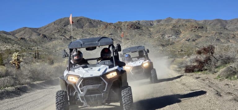 RZR off-road vehicles race on a dusty Nevada trail near Las Vegas, surrounded by desert mountains and shrubs—top ATV tour adventure.
