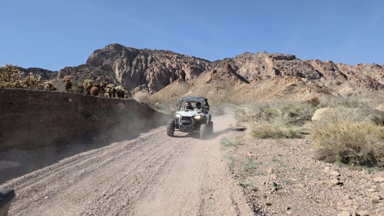 ATV drives on a dusty desert trail near Las Vegas, Nevada, with rugged mountains—ideal for RZR rides or Ghost Town tours.