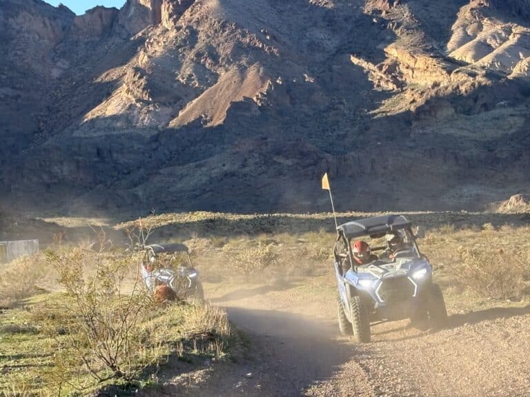 ATV off-road vehicles on a dusty Nevada desert trail near Las Vegas, with rocky mountains and sparse vegetation in view.