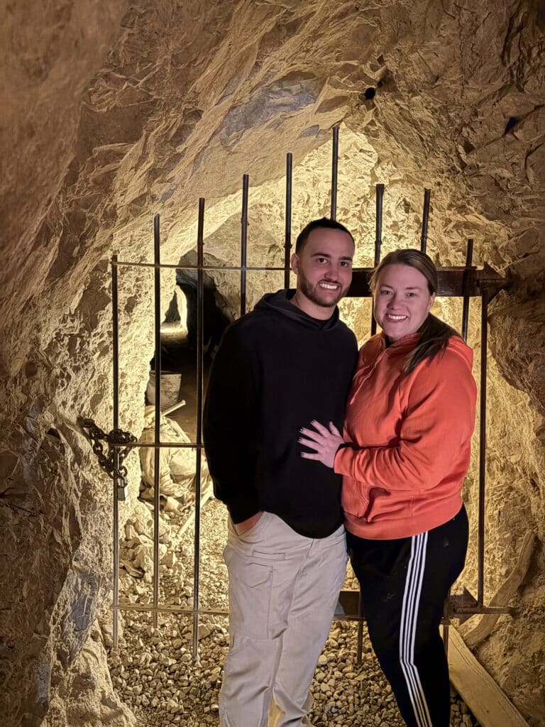 Smiling couple at a cave gate near the Colorado River, Nevada, after an exciting ATV tour adventure.