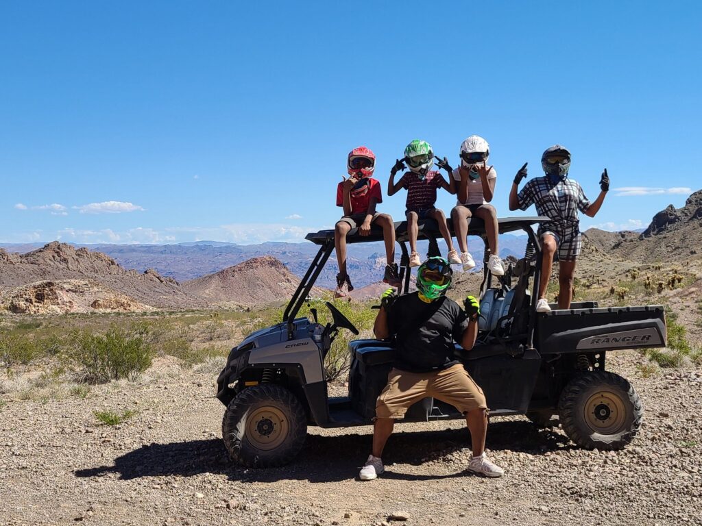 Group in colorful helmets poses on ATV during a Las Vegas Nevada off-road tour by the Colorado River, enjoying desert adventure.