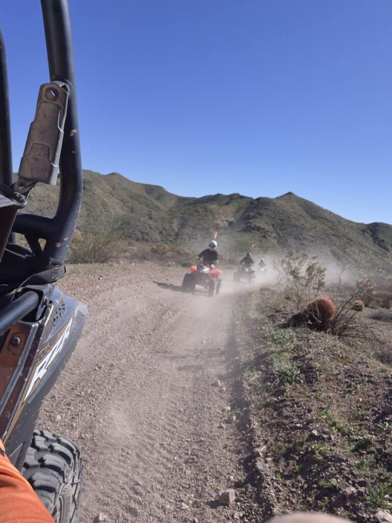 ATV riders explore a dusty desert trail near Las Vegas, Nevada, with mountain views under blue skies—perfect for off-road tours.