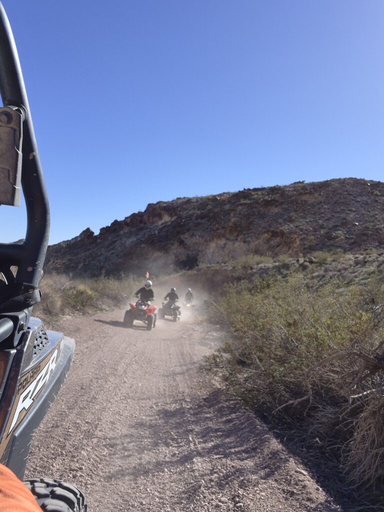 Adventurers enjoy an ATV tour near Las Vegas, riding dusty desert trails with Nevada’s rocky hills and clear blue skies.