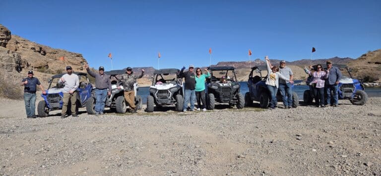 Friends celebrate by off-road vehicles on the Colorado River near Las Vegas, enjoying an ATV tour against Nevada's rocky hills.