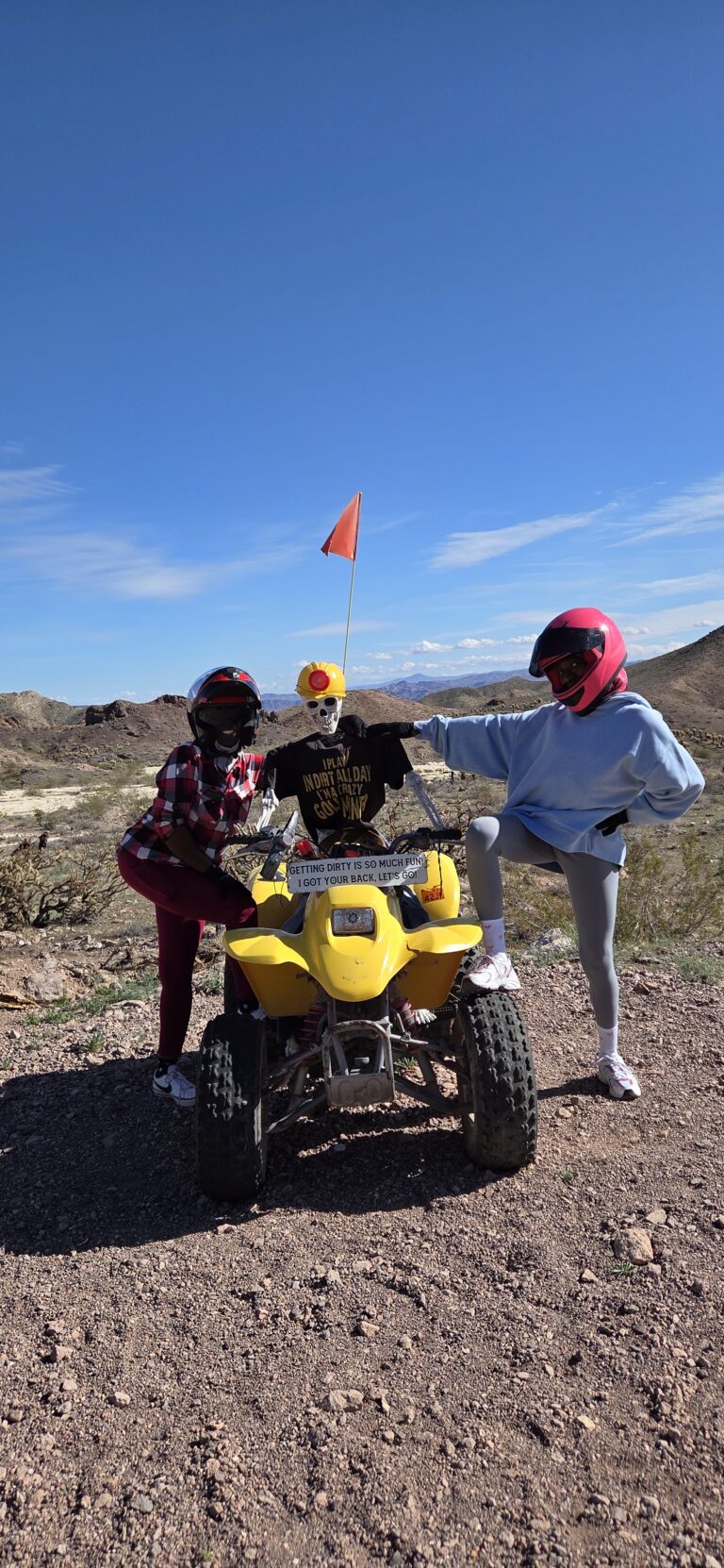 Two helmeted riders pose by a yellow ATV on a rocky Nevada trail near Las Vegas, ready for an ATV tour adventure.