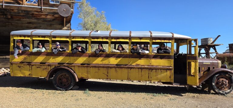 Adventurers relax in a vintage yellow bus near a Nevada ghost town, perfect for Las Vegas ATV tours and Colorado River views.
