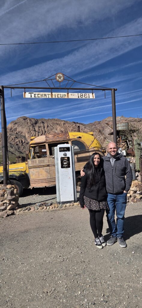 Couple smiles by a vintage truck in Techatticup Ghost Town, Nevada, near Las Vegas—perfect for sightseeing and ATV tours.