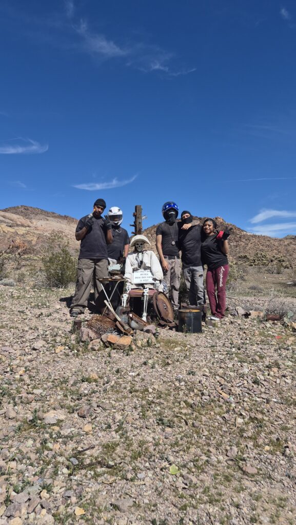 Group poses near a mannequin in rocky Nevada desert with mountains; perfect for Nevada ATV or RZR off-road tours near Las Vegas.