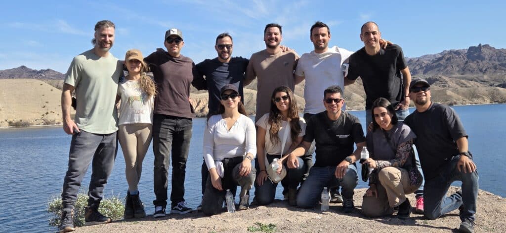 Group of twelve poses by the Colorado River near Las Vegas, Nevada, with mountains behind; perfect for ATV tours and sightseeing.