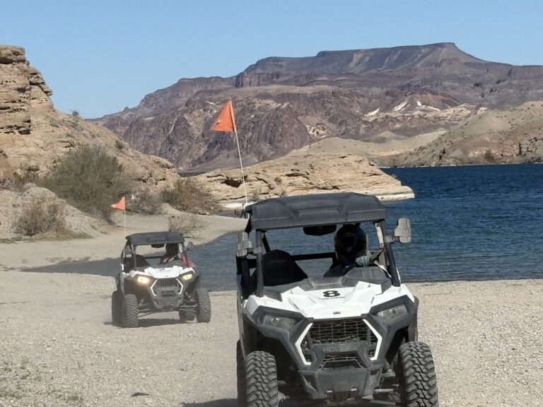 ATVs with orange flags drive by the Colorado River near Las Vegas, Nevada, amid desert cliffs—perfect for RZR off-road tours.
