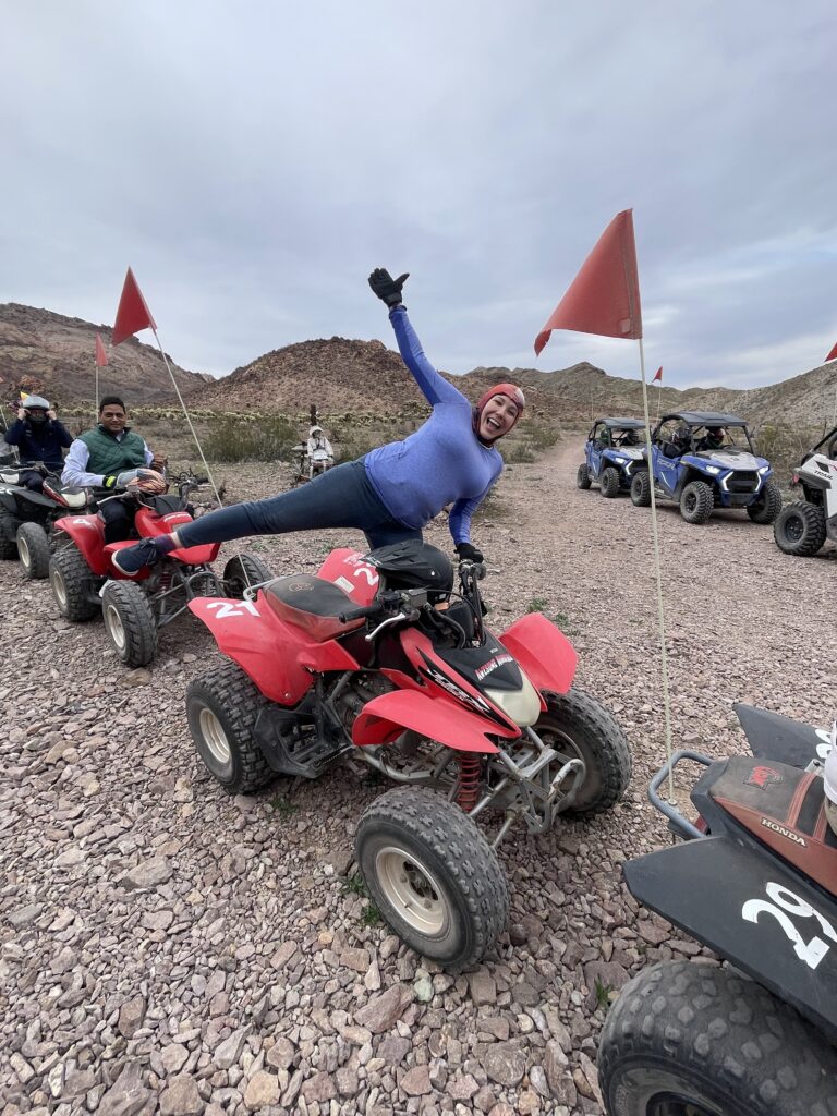 Adventurer in blue poses on red ATV during a thrilling Nevada off-road tour near Las Vegas and the scenic Colorado River.