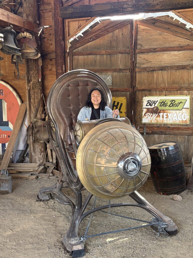 Smiling visitor on a steampunk time machine in a Nevada barn, perfect for Ghost Town sightseeing near Las Vegas and Colorado River.