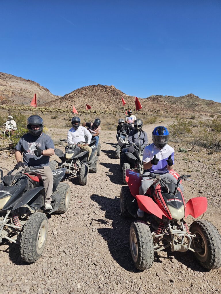 ATV riders in helmets line up on a rocky Nevada desert trail near Las Vegas, ready for an exciting off-road tour under blue skies.