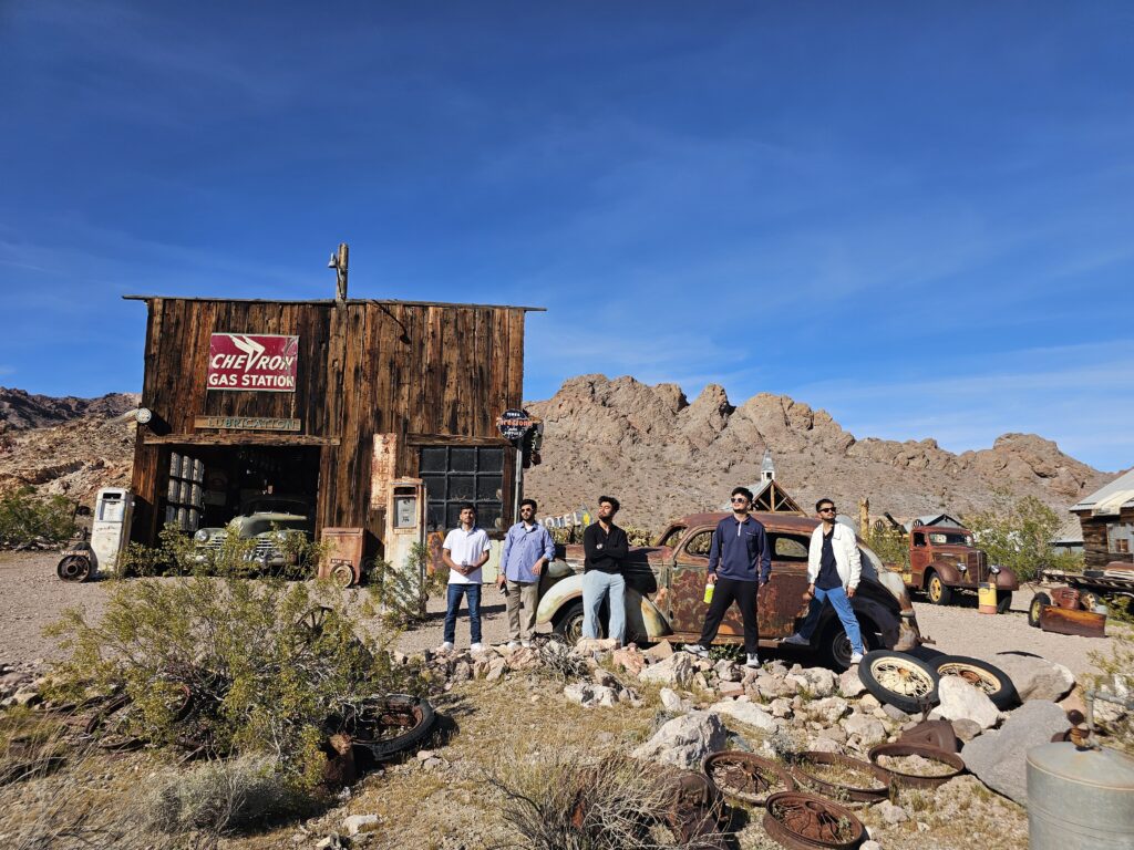 Group posing at a vintage Nevada gas station with old cars, near Las Vegas ghost towns—perfect for ATV tours and sightseeing.