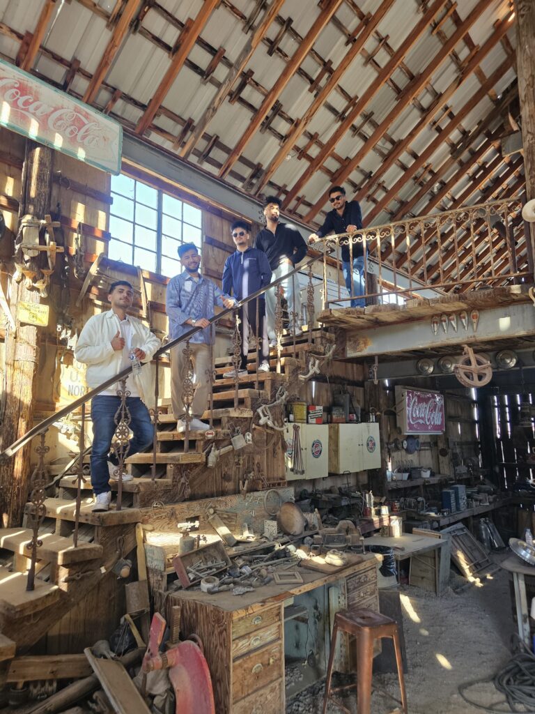 Five men pose on a wooden staircase in a rustic Nevada workshop—perfect for Las Vegas Ghost Town sightseeing adventures.