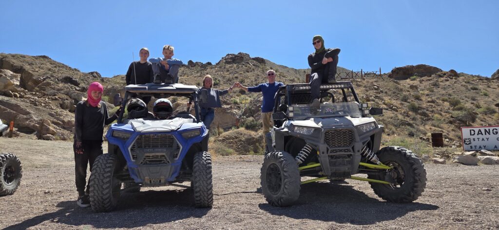 Adventurers on a Nevada ATV tour pose with off-road vehicles in a rocky desert near Las Vegas and the Colorado River.