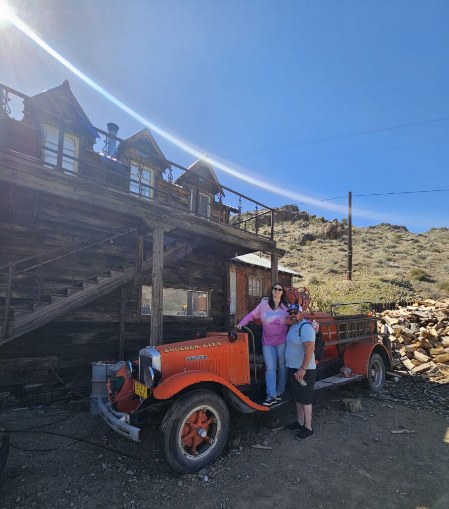 Two people by a vintage red Riverside City fire truck at a Nevada ghost town near Las Vegas, perfect for sightseeing adventures.