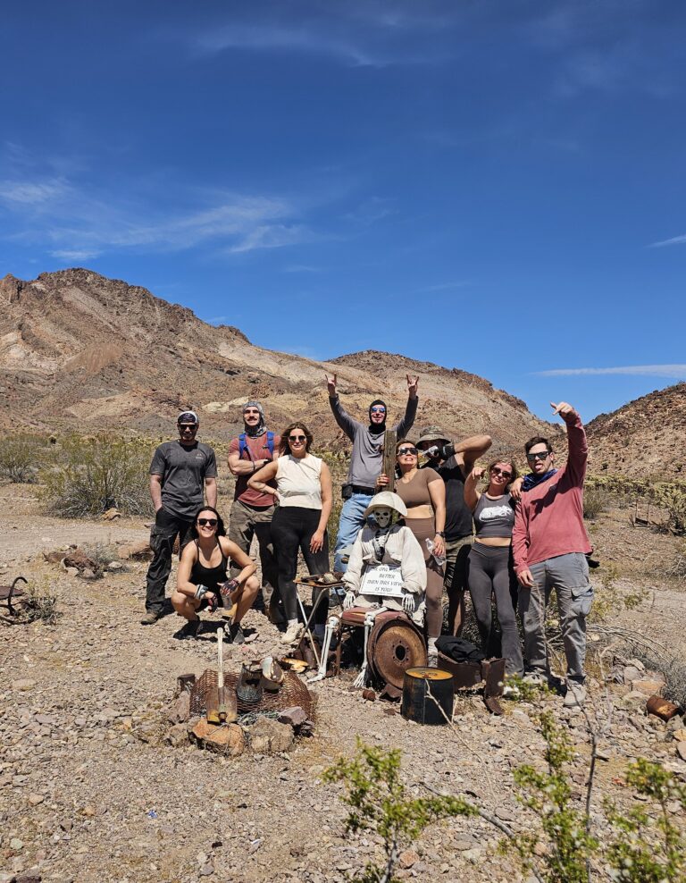 Group poses in Nevada desert near Las Vegas, mannequin amid relics—perfect for Ghost Town sightseeing and ATV adventure.