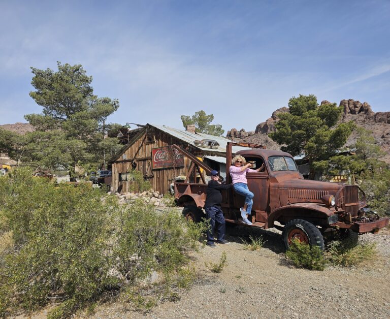 Friends pose on a rusty truck in a Nevada ghost town near Las Vegas—perfect for sightseeing or ATV tours by the Colorado River.