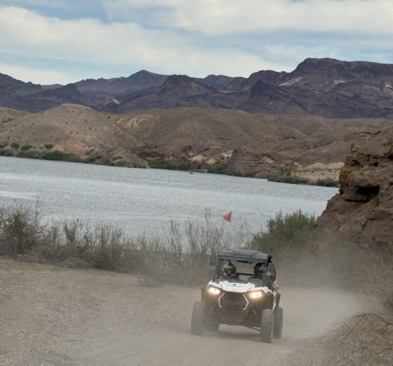 Experience an exhilarating RZR off-road ride near Las Vegas by the Colorado River, with rugged Nevada hills and a scenic lake backdrop.