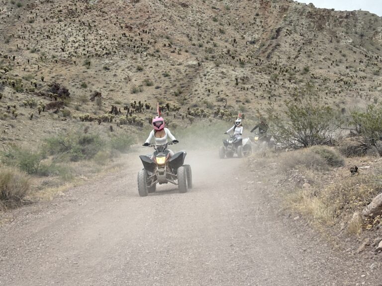 ATV riders on a dusty Nevada desert trail near Las Vegas, exploring rocky hills and enjoying an exciting RZR off-road tour.