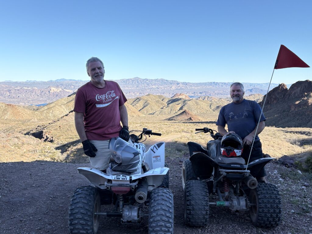 Two men ride ATVs on a Nevada trail near the Colorado River, enjoying scenic mountain views on a Las Vegas ATV tour.