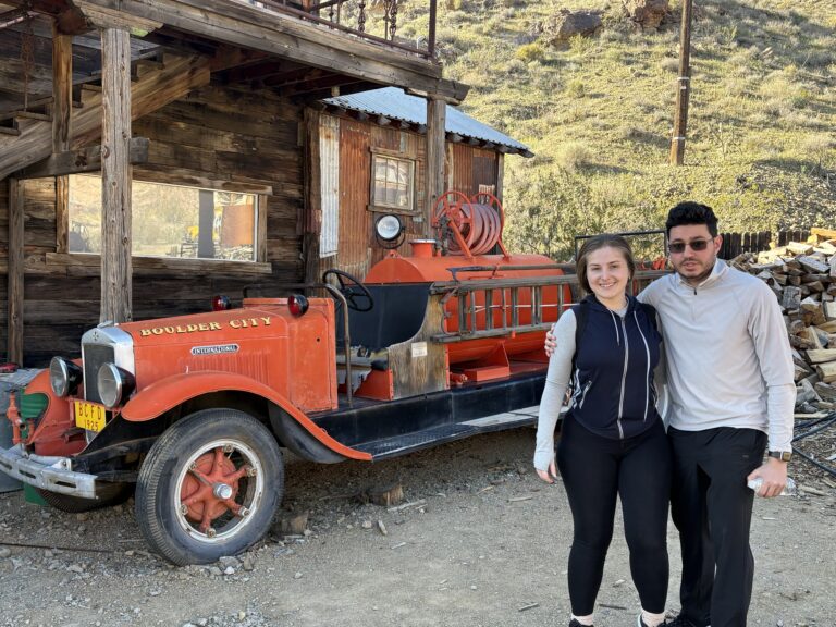 Smiling duo by vintage Boulder City fire truck in rural Nevada near Las Vegas—perfect for Ghost Town sightseeing or ATV tours.